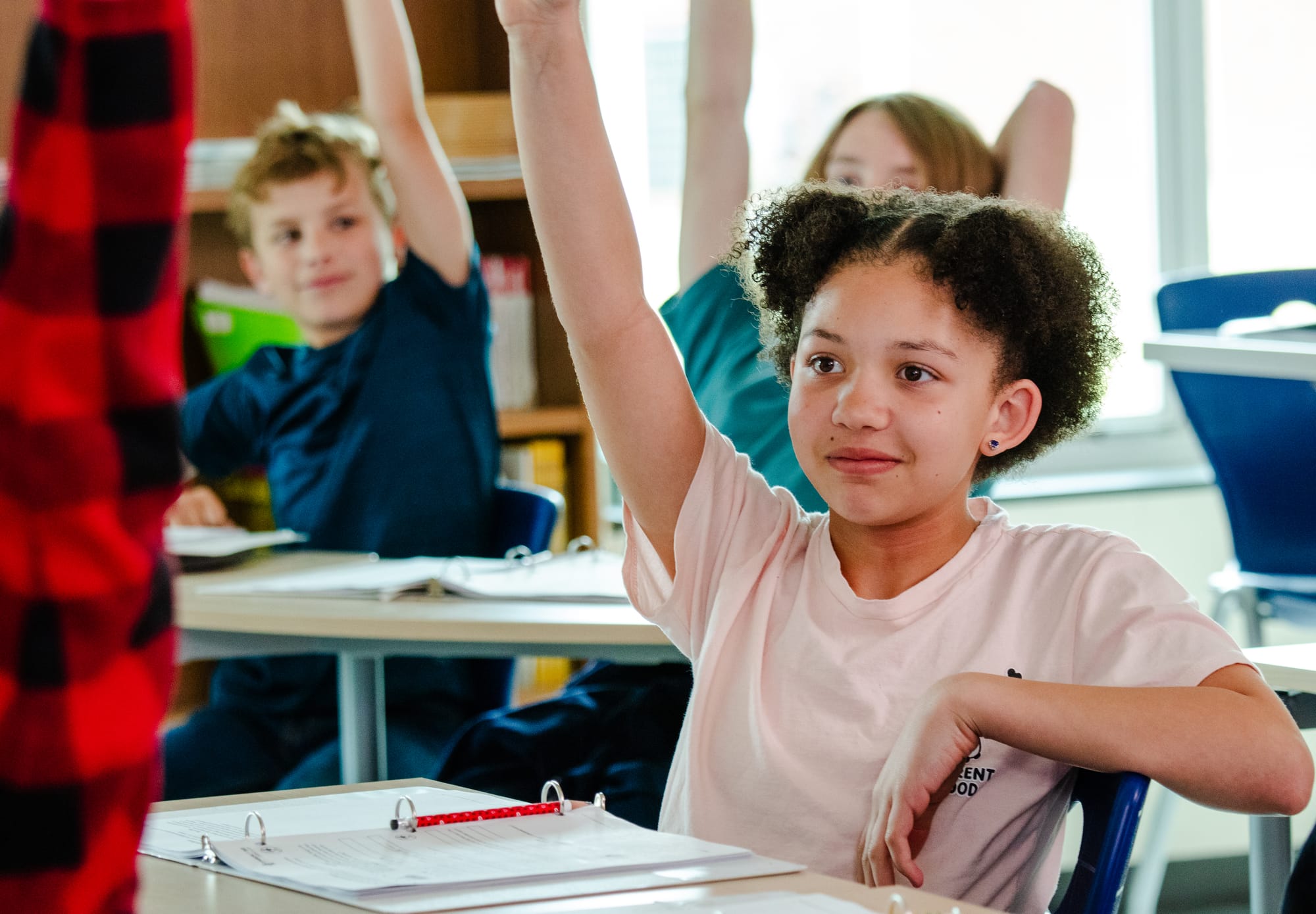 Students raise their hands in a 6th grade ELA class at Cape Fear Middle School.